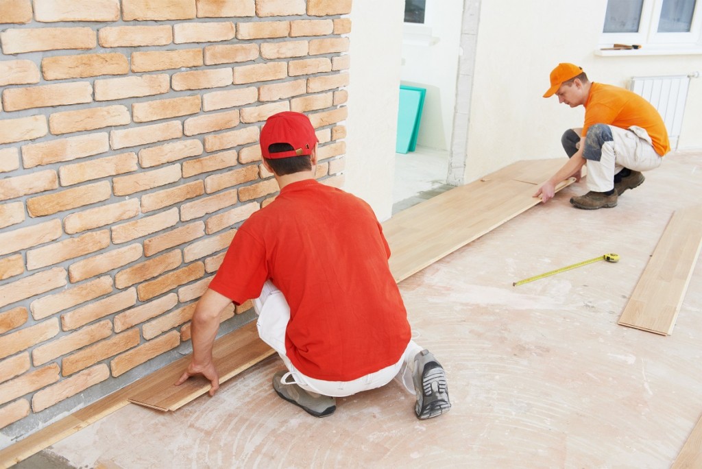 Two parquet carpenter workers installing wood board during flooring work